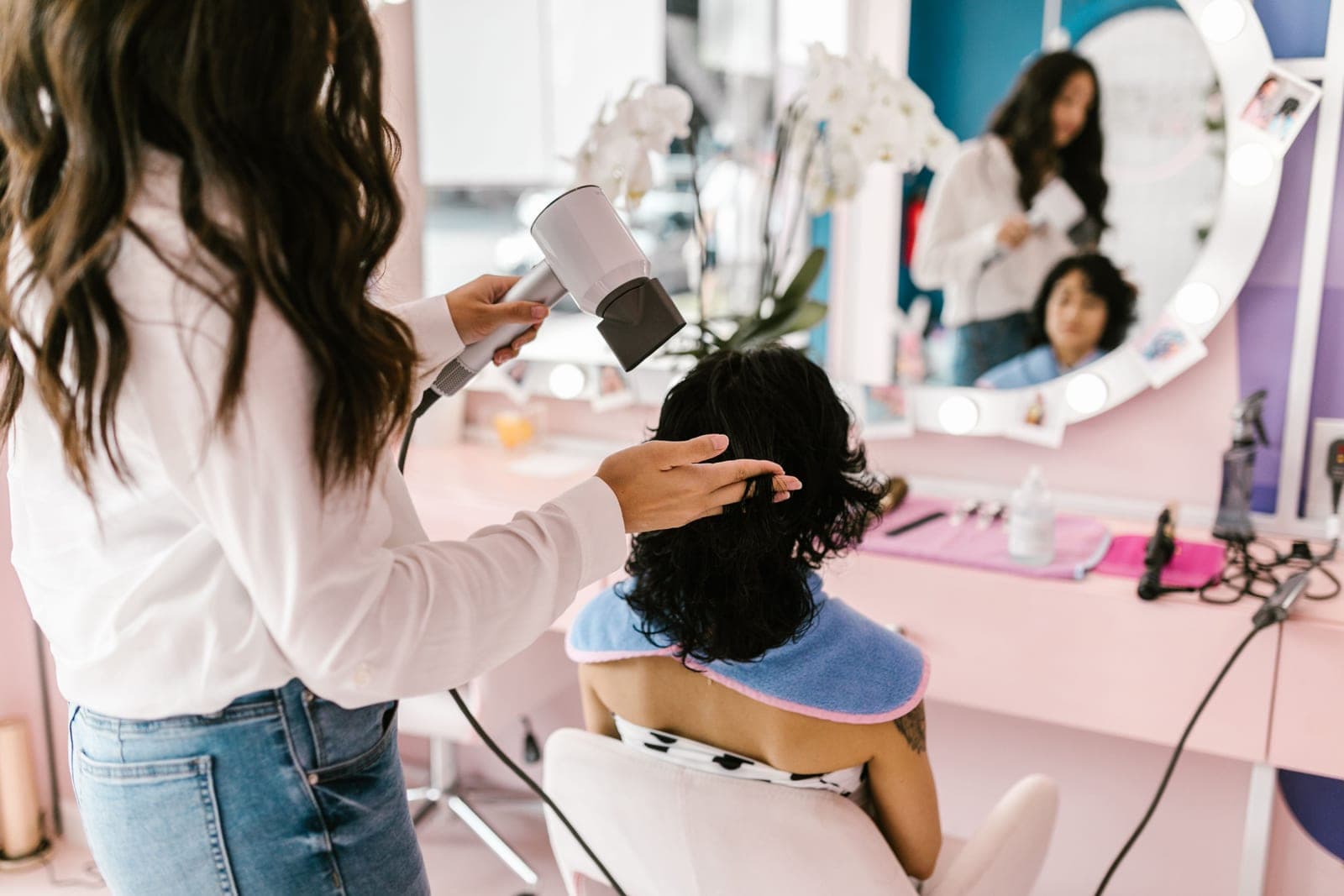 A hairdresser blow drying a client's hair in a salon