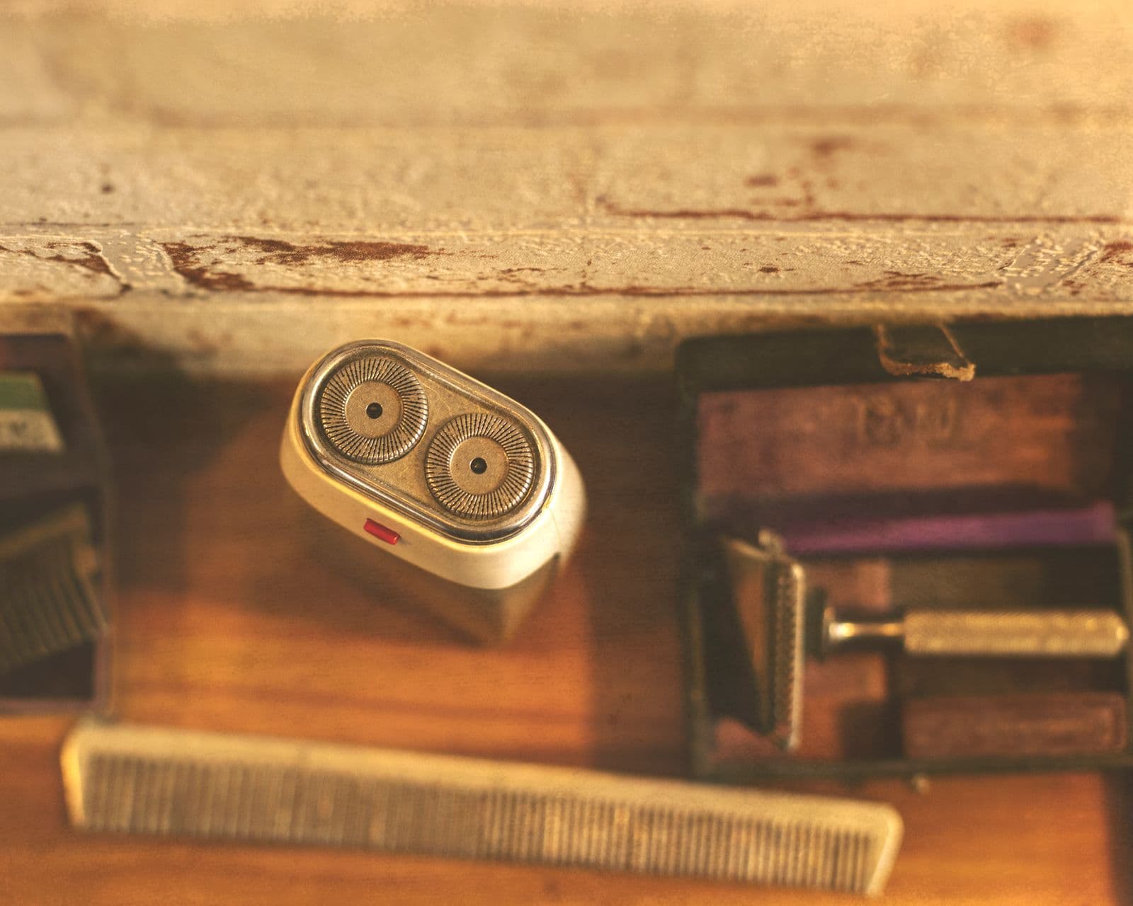 An electric shaver and grooming tools on a wooden surface