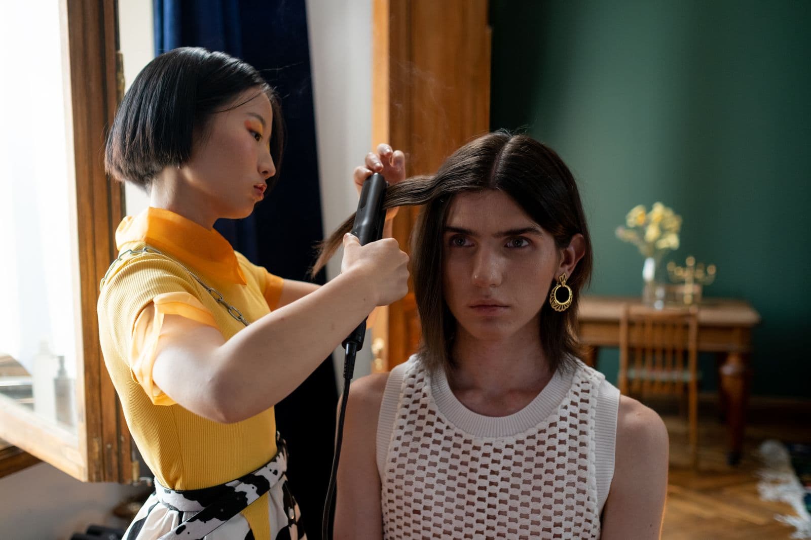 A stylist straightening a section of hair with a flat iron
